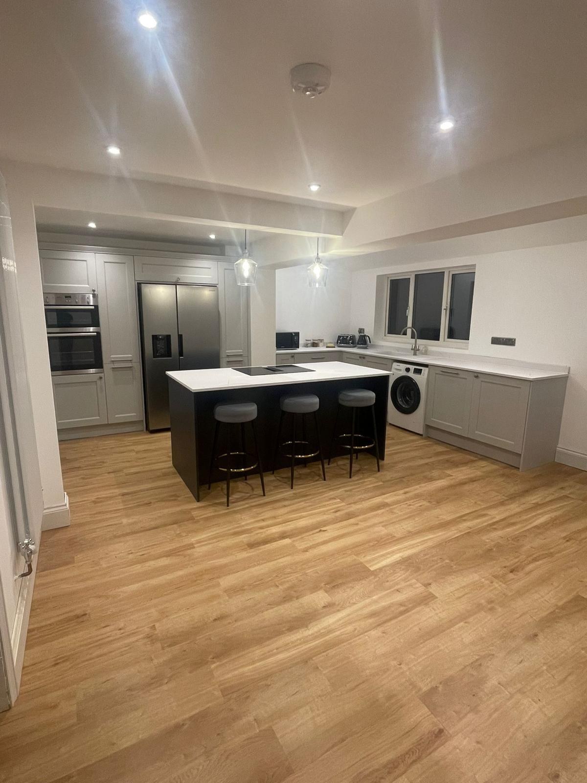 Grey shaker kitchen with dark island, breakfast bar seating and oak flooring, Prime Build Services kitchen fitting