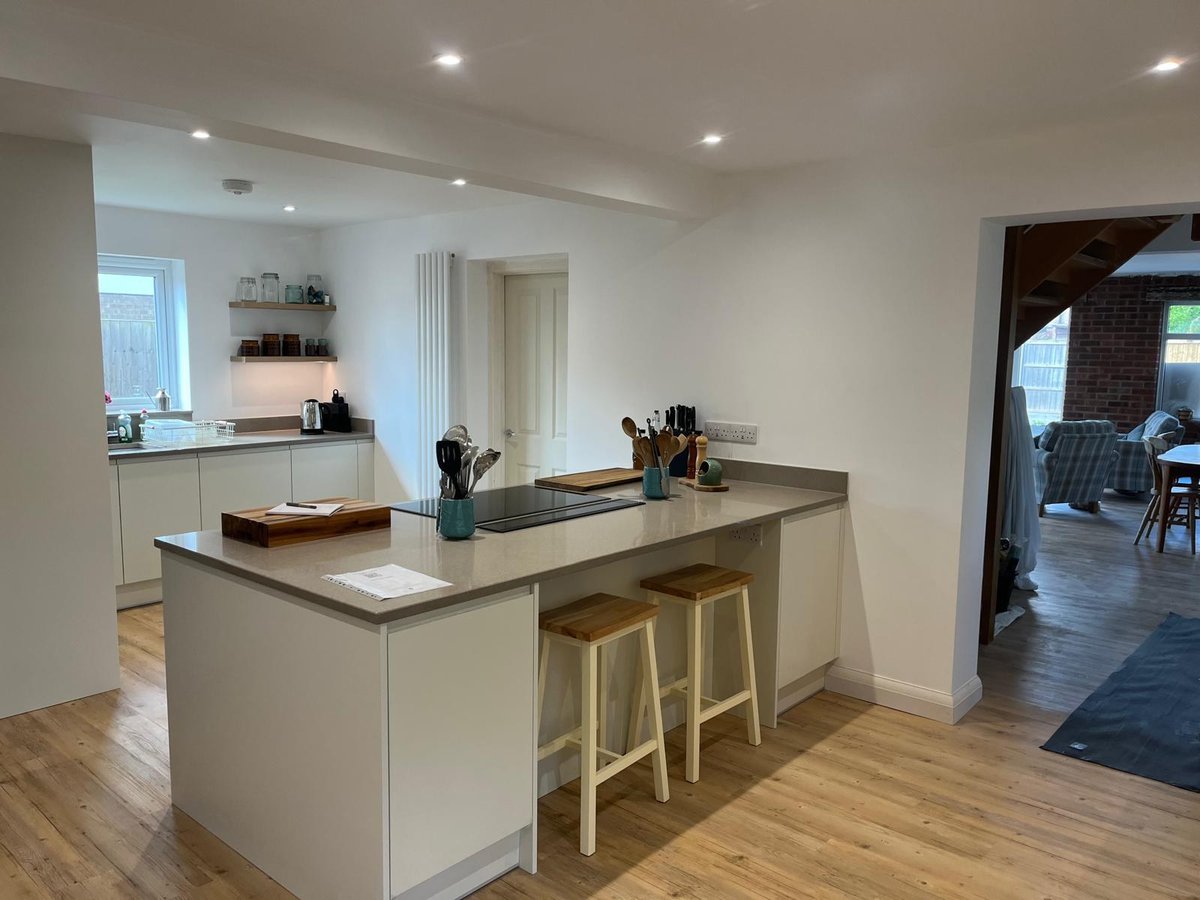 Handleless cream kitchen with peninsula breakfast bar and oak flooring, Prime Build Services kitchen fitting