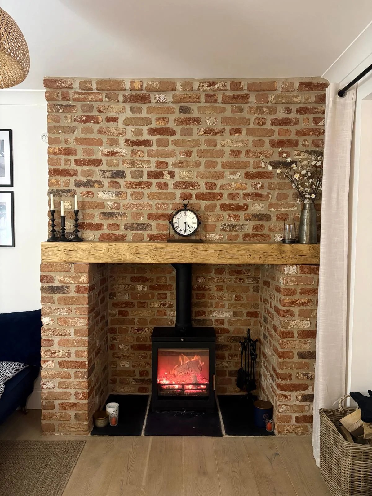 Completed reclaimed brick fireplace with oak mantel and wood-burning stove